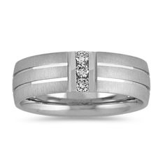 This dynamic 7mm men's wedding ring features three round diamonds  at approximately .15 carat total weight  that were hand-matched for consistent fire and sparkle. The diamonds are channel-set in quality 14 karat white gold with both brushed and polished finishes. Round Diamond Wedding Band, White Gold Diamond Band, Round Diamonds Wedding Band, Wedding Organizer Planner, Gold Diamond Band, Men's Wedding Ring, Platinum Jewelry, Diamond Wedding Band, Channel Set