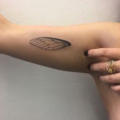 a woman's arm with a black and white butterfly wing tattoo on the left forearm