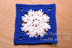 a crocheted square with a snowflake on the center and white flowers in the middle