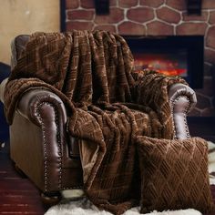 a chair with a blanket on it in front of a fire place