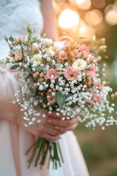 a bride holding a bouquet of pink and white flowers