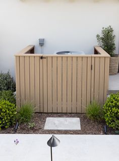 an outdoor hot tub in the middle of a garden with plants and shrubs around it