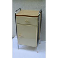 a small white cabinet with two drawers on it's sides and a metal frame around the top