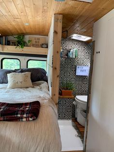 a small bedroom with a bed, sink and toilet in the back wall is made out of wood planks