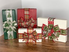 three wrapped presents sitting on top of a wooden table next to each other with bows