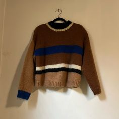 a brown and blue striped sweater hanging on a white wall next to a hanger