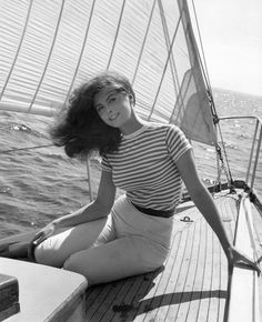 a woman sitting on the deck of a sailboat