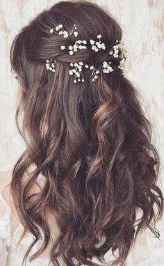 the back of a woman's head with long hair and flowers in her hair