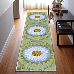 a green and white rug with flowers on it in the middle of a wooden floor