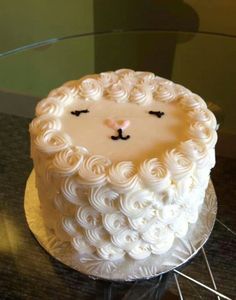 a cake with white frosting and a cat face on it's side sitting on a glass table