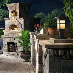 an outdoor fireplace with potted plants and lights