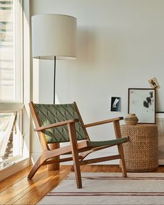 a wooden chair sitting in front of a window next to a lamp