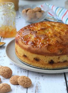 a cake sitting on top of a white plate next to cookies and honey syrups