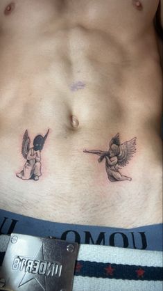 a man's chest with two small angel tattoos on his chest and the bottom half of his stomach