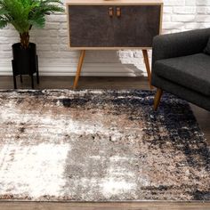 a living room area with a chair, rug and side table in front of a white brick wall