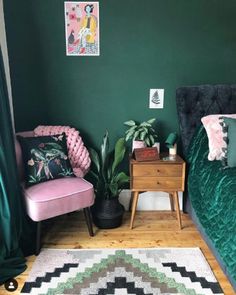 a bedroom with green walls and pink chair next to a rug on the wooden floor