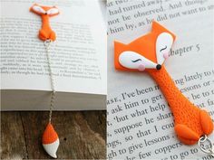 an orange fox keychain is shown on top of a book and the bottom one has a chain attached to it