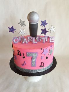 a pink birthday cake decorated with musical notes and a microphone