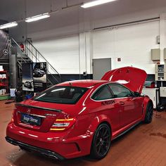 a red car parked in a garage with its hood open