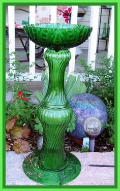 a green glass water fountain sitting in the middle of a garden