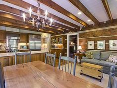 an open concept kitchen and living room with wood beams on the ceiling, hardwood flooring