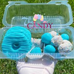 a plastic container filled with blue and white donuts on top of a lush green field