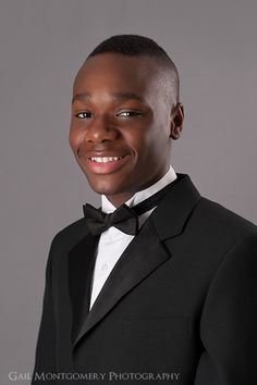 a young man in a tuxedo poses for a photo wearing a bow tie