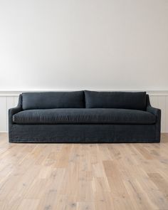 a couch sitting on top of a hard wood floor next to a white painted wall