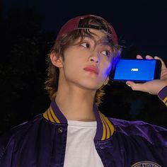 a young man is holding up his cell phone