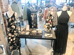 dresses and jewelry are on display in a clothing store, with mannequins behind them