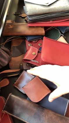 a person is pointing at several different types of wallets in a drawer with one hand on top of the other