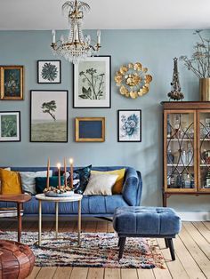 a living room with blue couches and pictures on the wall above it, candles in front of them