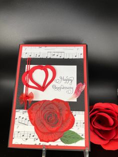 a red rose sitting on top of a table next to a piece of music paper