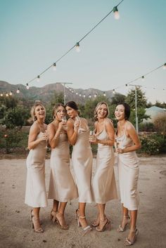 the bridesmaids are all dressed in beige dresses and high heels, posing for a photo