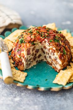 a cheese ball covered in toppings on top of a blue plate with crackers