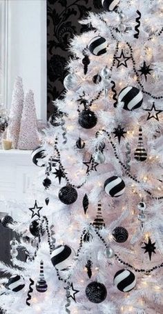 a white christmas tree decorated with black and silver ornaments