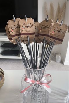 a glass vase filled with lots of black and silver straws on top of a table