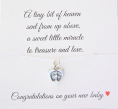 a card with a silver heart and two baby feet attached to the back of it