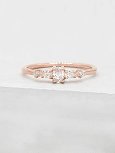 an engagement ring with three stones on the front and side, set in rose gold