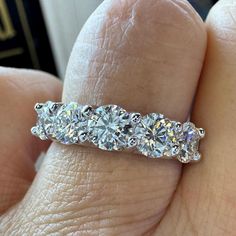 a woman's hand holding a three stone diamond ring