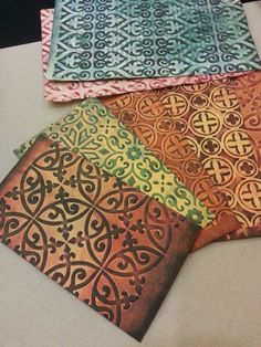 four different colored papers with designs on them sitting next to each other in a row