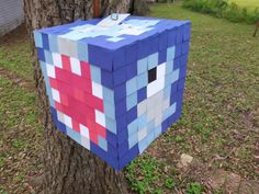 a blue and red block shaped like a face is attached to a tree in the yard