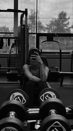 a woman taking a selfie in front of a gym machine with her cell phone