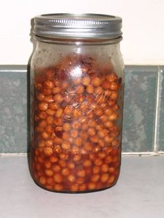 a glass jar filled with beans sitting on top of a counter