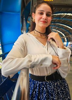 a woman in a white shirt and blue skirt posing for the camera with her hands on her hips