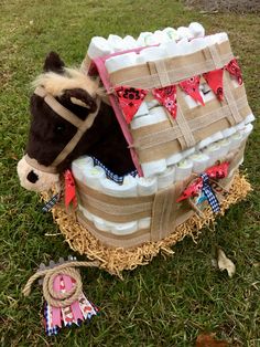 a stuffed horse in a basket on the grass with other items around it that include ribbons and bows