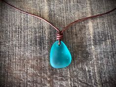 a necklace with a blue tear hanging from it's end on a wooden surface