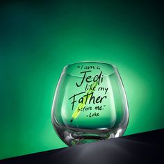 a wine glass with writing on it sitting on a table next to a green background