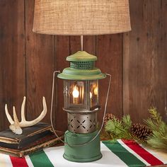 a green lamp sitting on top of a table next to a book and antlers