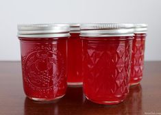 three jars with red liquid are sitting on a table